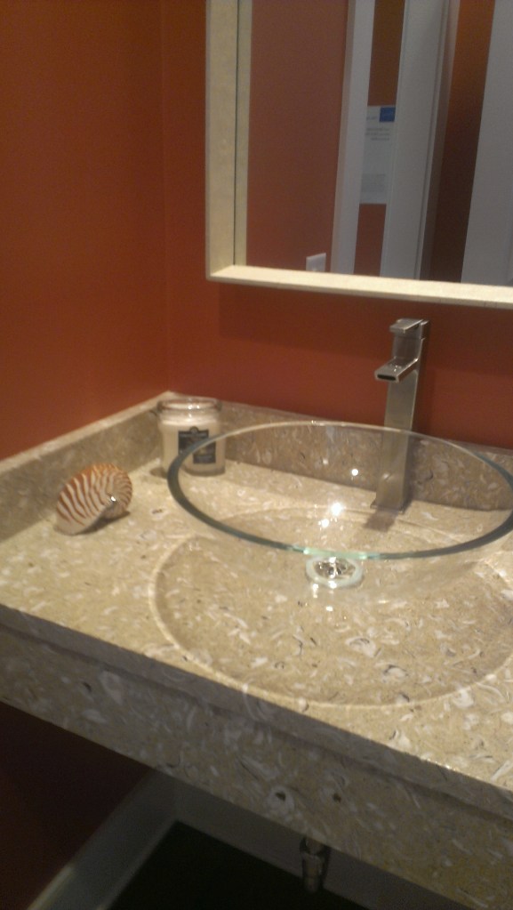 Powder room on main. Love the fossil or shell material, not sure if its stone or fabricated?
